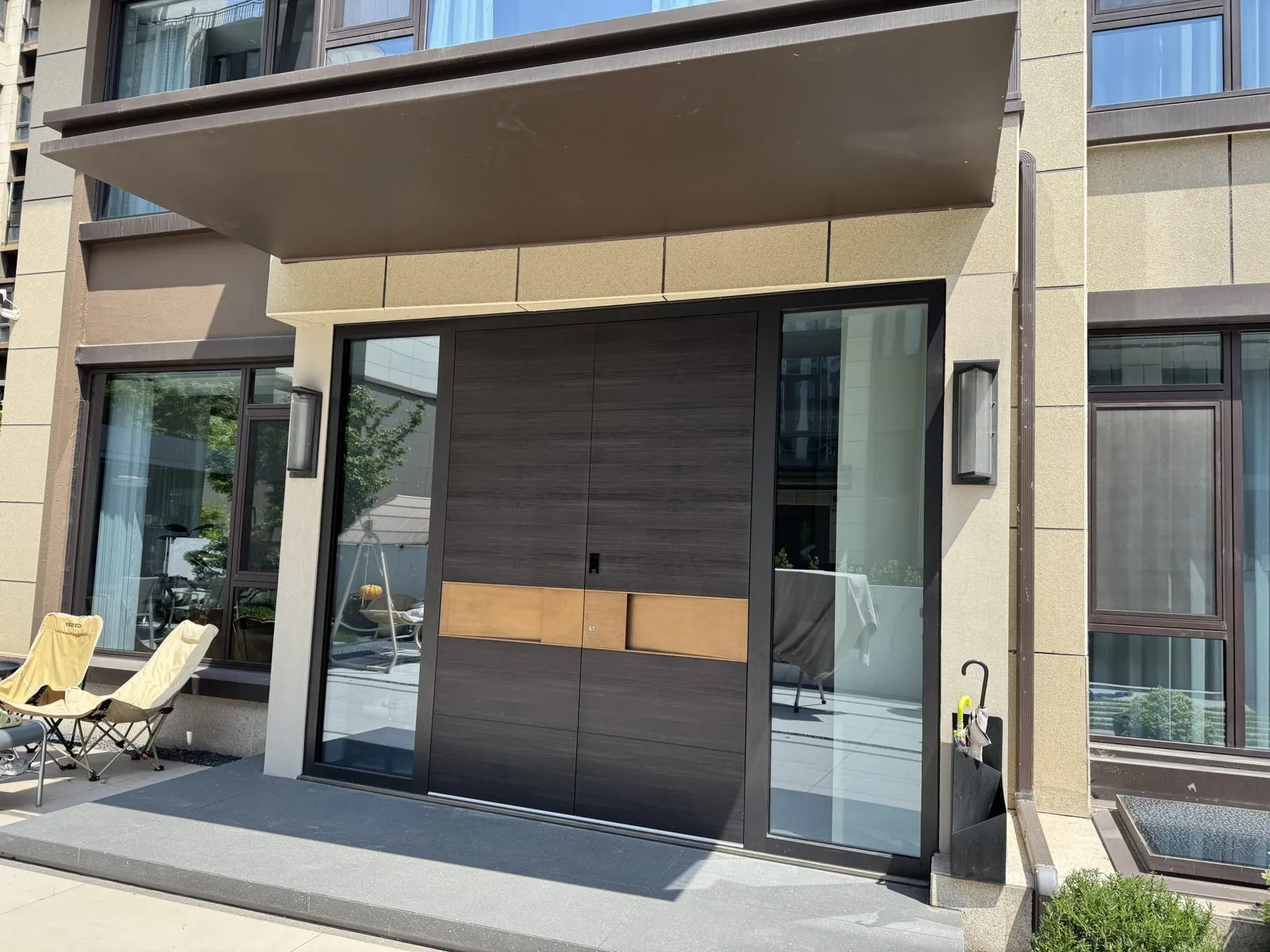 Dark vertical-grain double door with a copper-tone band, fitted between glass side panels.