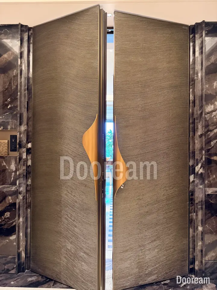 Metal-textured double door with folded gold handles at the centre, installed