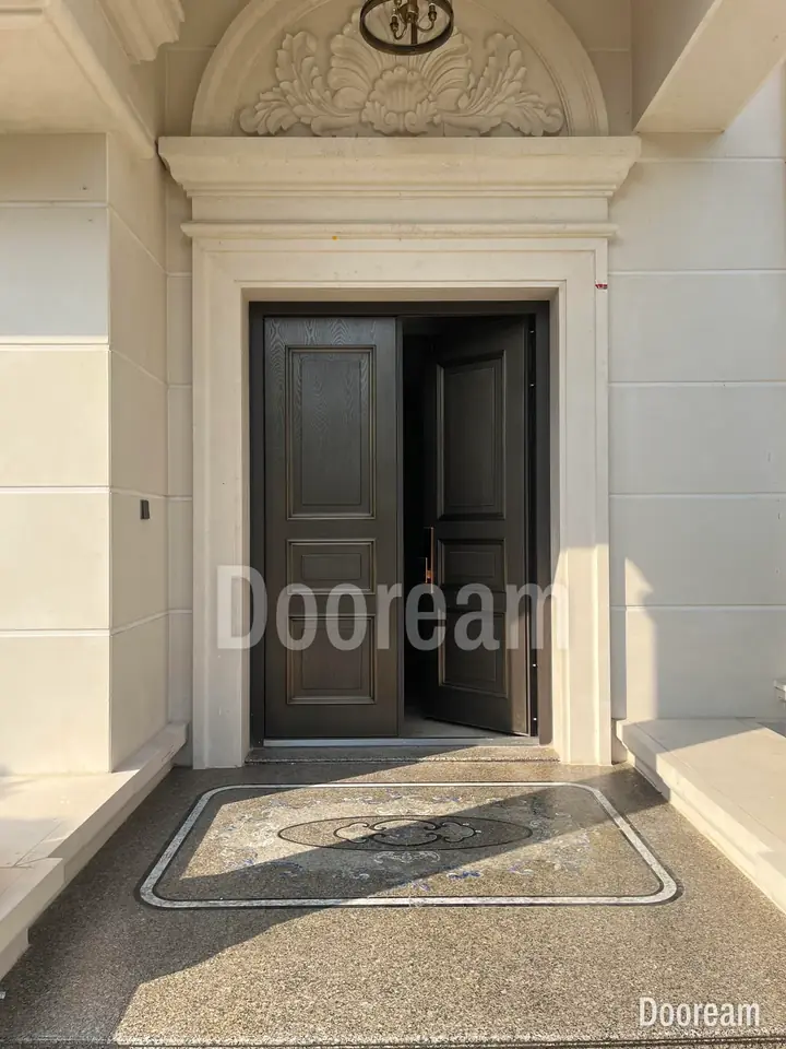Dark classic double door under an arched, ornamented porch, installed