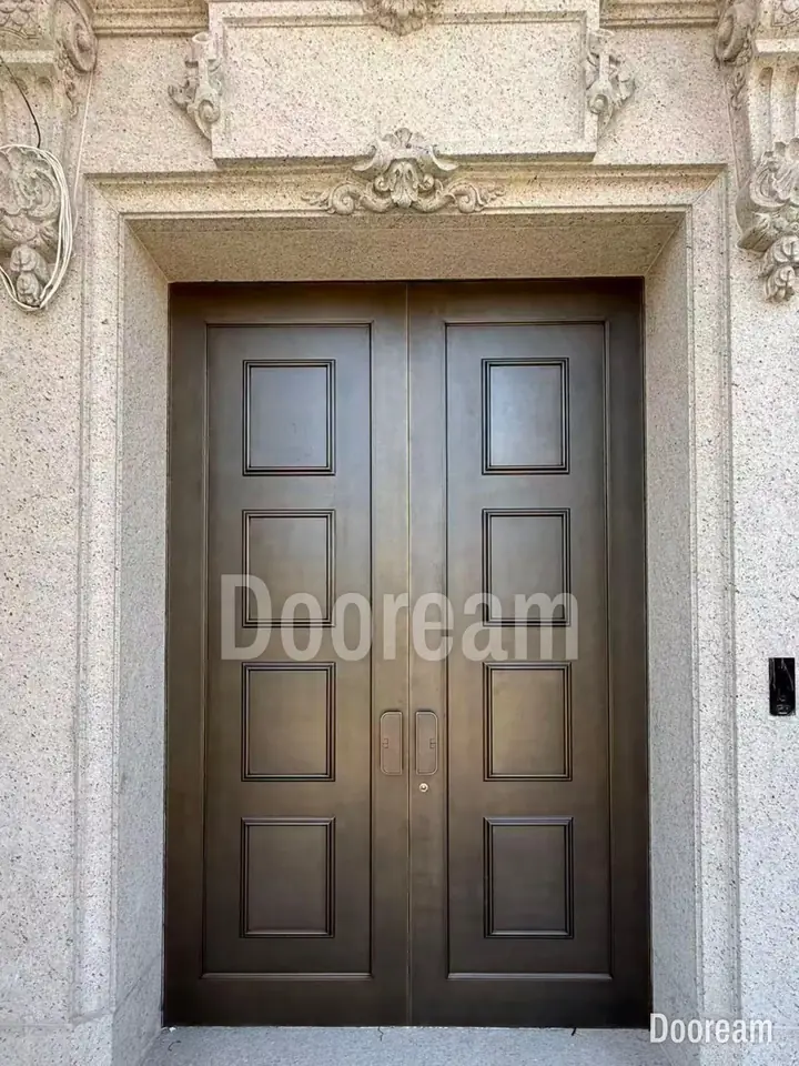 Dark double door with square panels, in a carved stone surround, installed