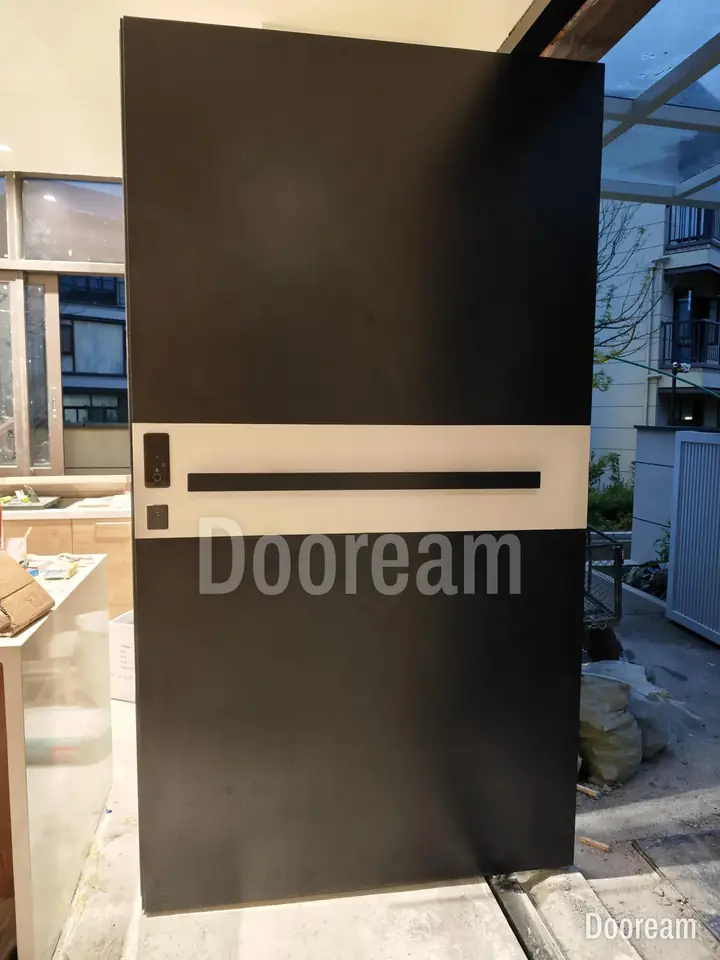 Black door with a silver band, on a pale facade, installed