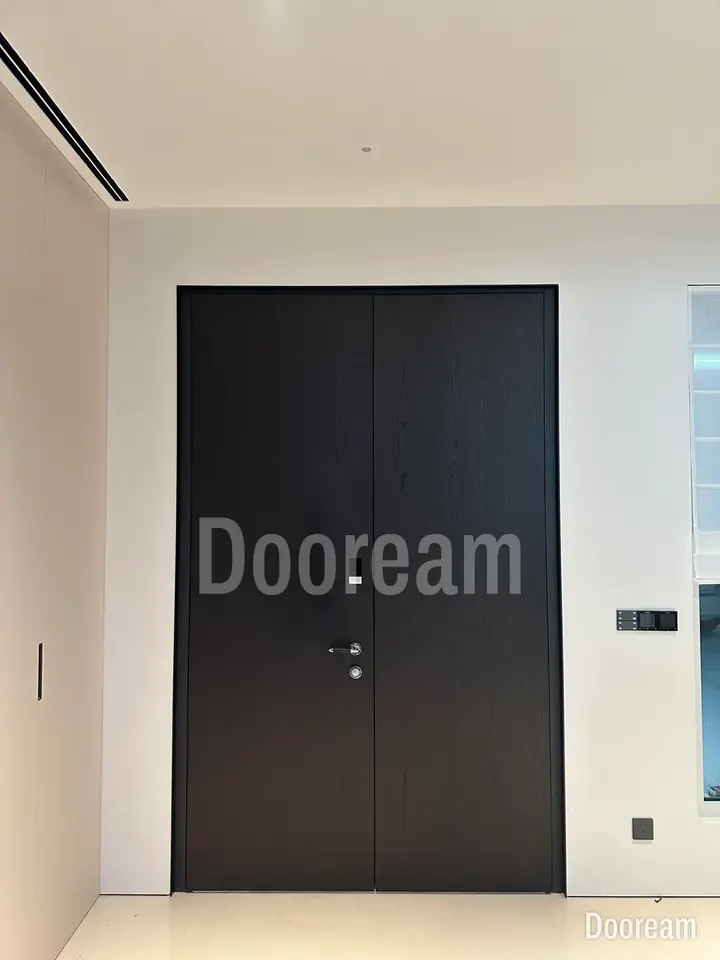 Dark minimalist door beside white walls and timber panelling, installed