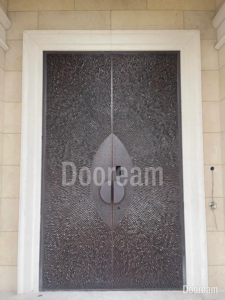 Dark-grey radial-texture door with a leaf-shaped centrepiece and round handle, installed