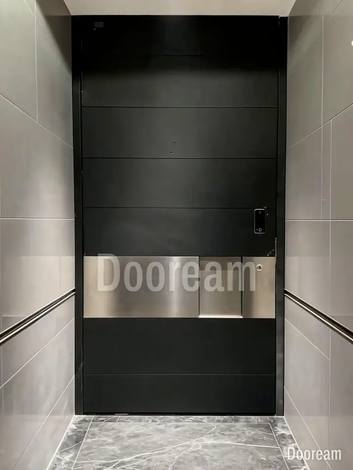 Black door with horizontal grooves and a wide silver metal band, against grey walls, installed
